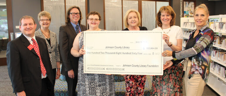 Johnson County Library Foundation Board members presenting a large check for the endowment of the Johnson County Library Collection in the total of $102,864.